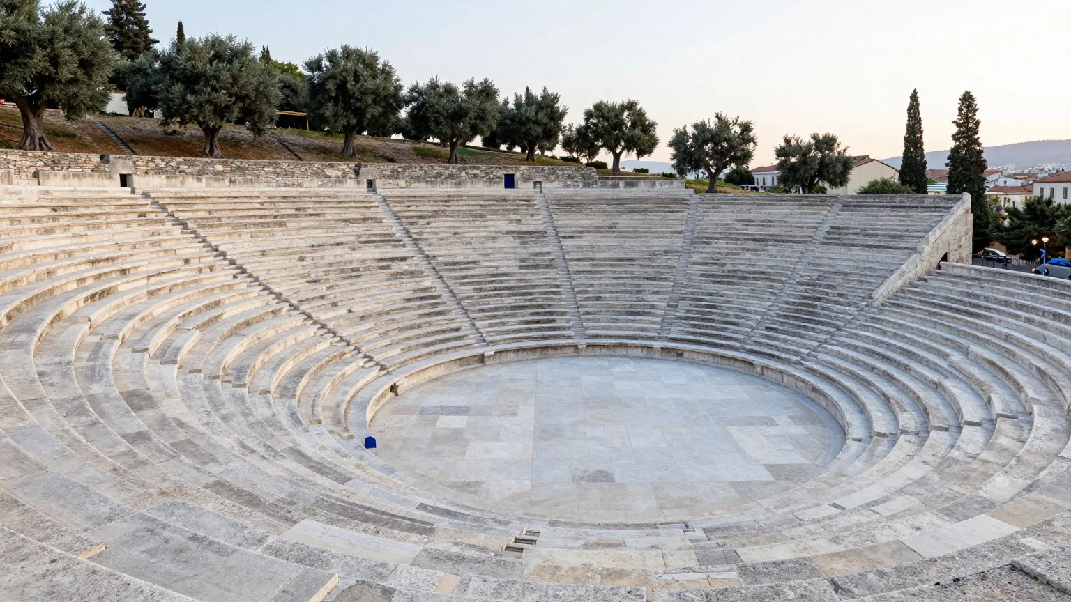 Ein antikes Steintheater an einem griechischen Hang bei Sonnenaufgang mit leeren Sitzreihen im Halbkreis